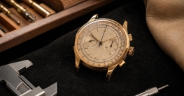 Ein goldener Chronograph mit Tachymeterskala liegt auf schwarzem Samt neben Messschieber und Werkzeugen.